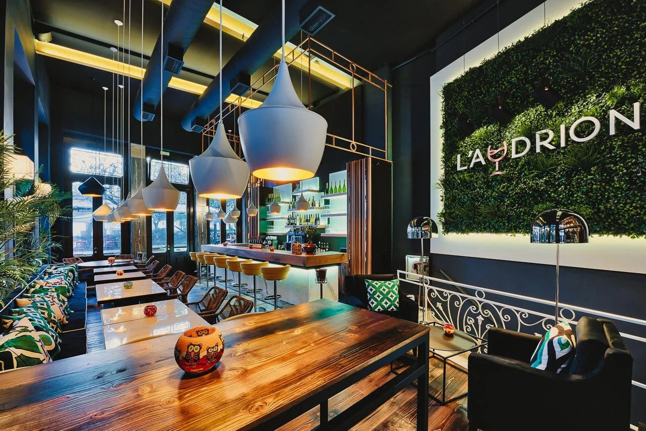 Εσωτερικο του Audrion Wine Bar με ξυλινα τραπεζια και κρεμαστα φωτιστικα στην Αθηνα