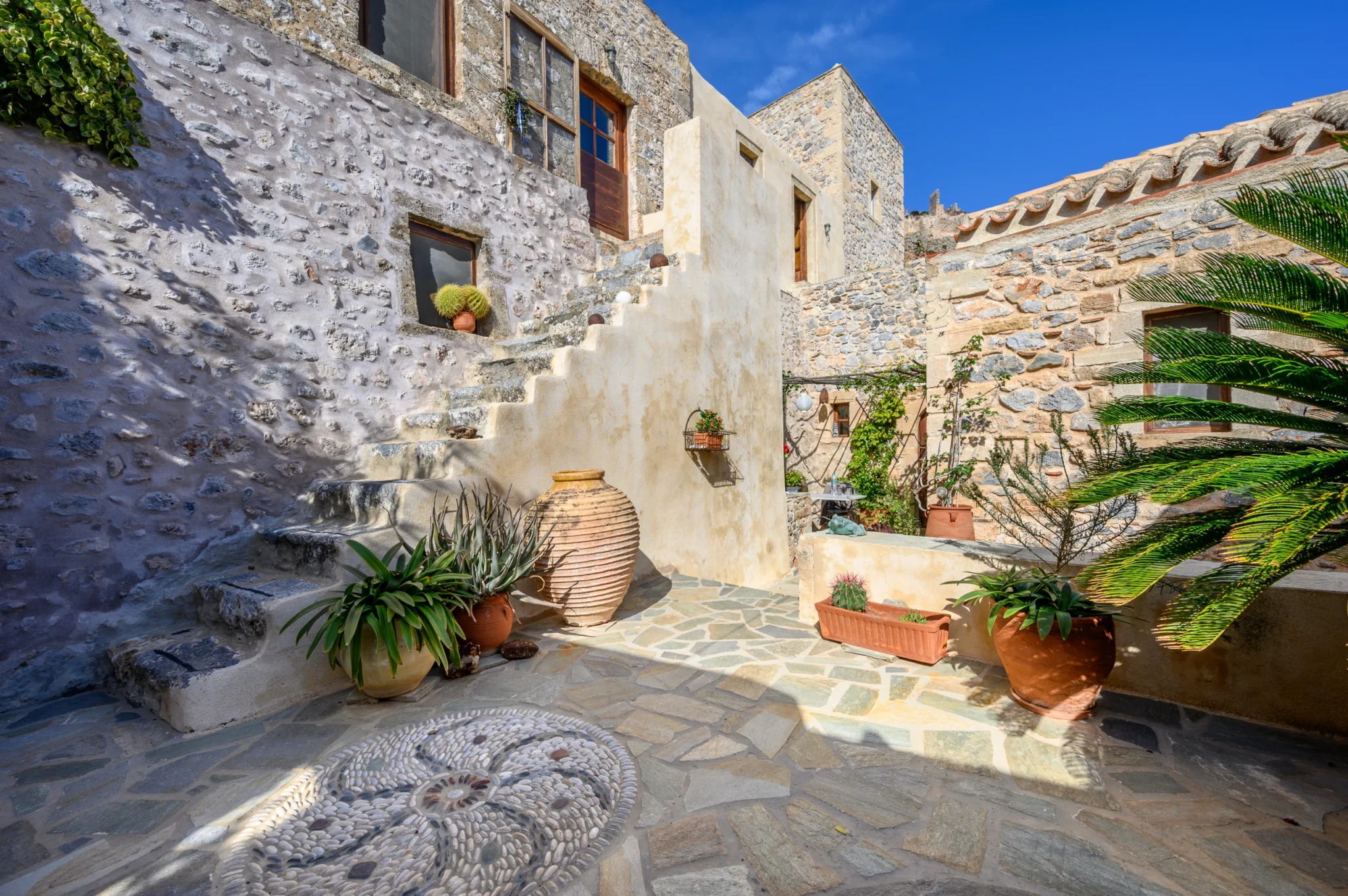 Πετρινη αυλη του Castle Residence με σκαλα και βοτσαλωτο στη Μονεμβασια