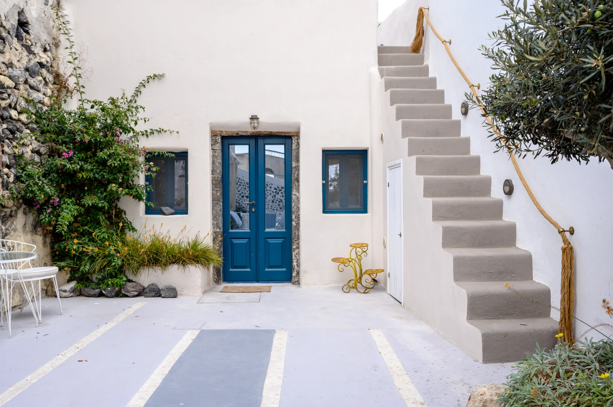 Αυλη με μπλε πορτα και λευκη εξωτερικη σκαλα στο Intermezzo