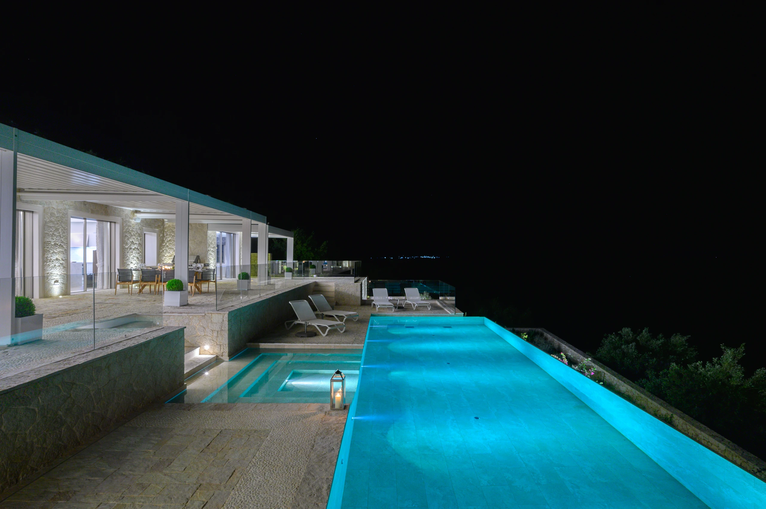 Φωτισμένη πισίνα και εσωτερικοί χώροι της Villa Artemis τη νύχτα