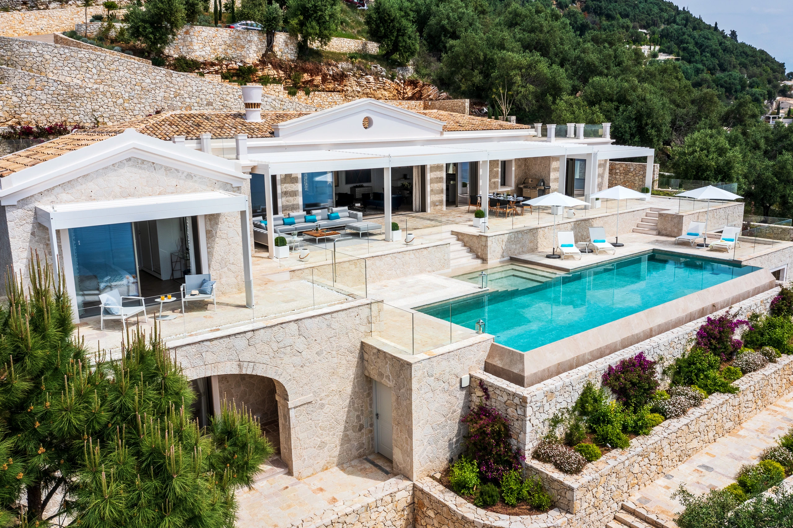 Εναέρια άποψη της Βίλας Άρτεμις στην Κέρκυρα, με την πέτρινη κατοικία, τις βεράντες και την πισίνα.