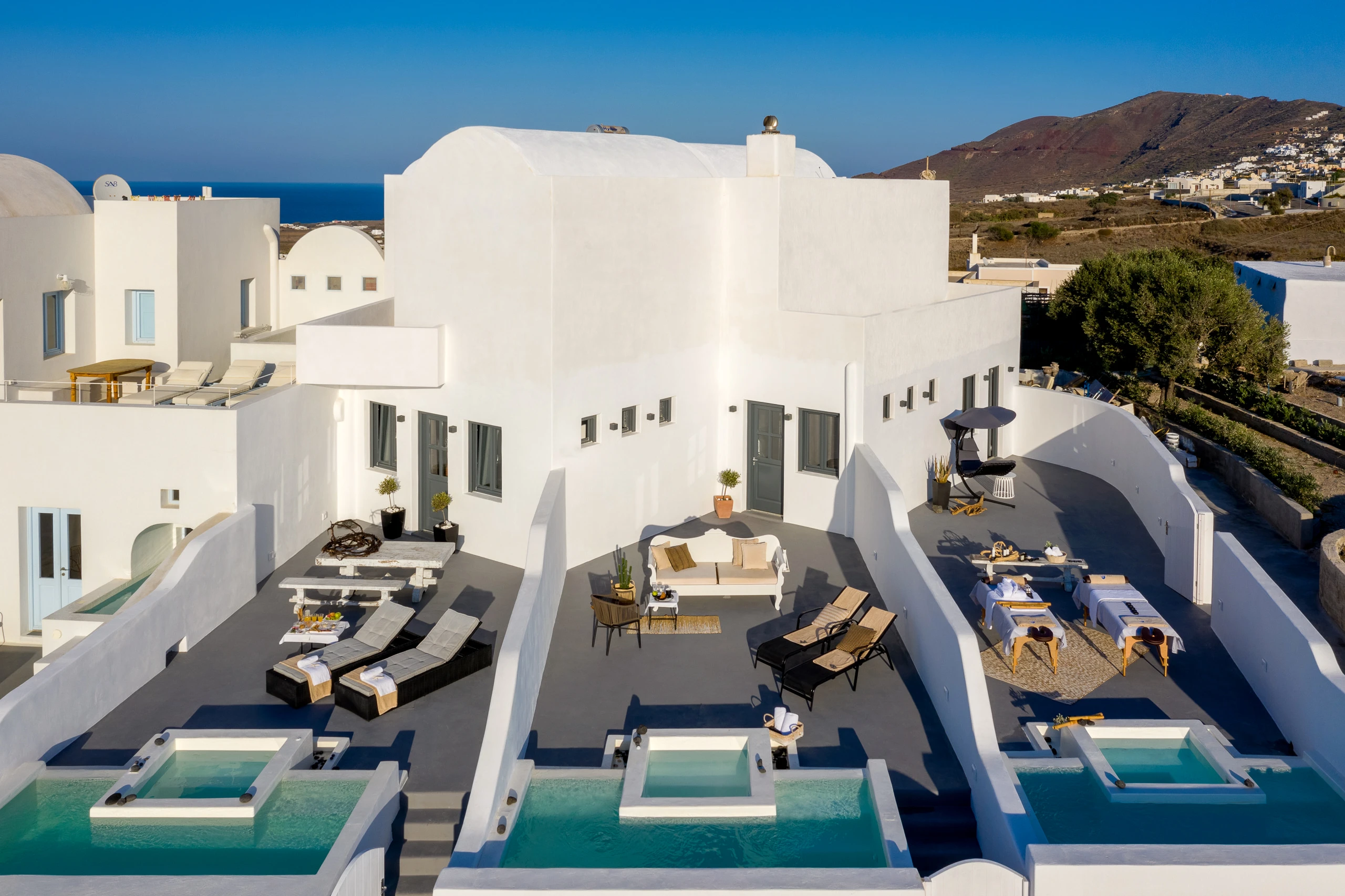 Εναέρια άποψη του Santolia Art Boutique Suites με λευκούς όγκους, βεράντες και ιδιωτικές πισίνες.